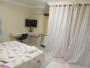 a bedroom with a bed and a desk and a television at 5C Hotel in Santo Antônio de Jesus