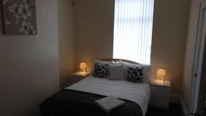 een slaapkamer met een bed met kussens en een raam bij South Shield's Hidden Gem Amethyst 3 Bedroom House Sleeps 6 Guests in South Shields