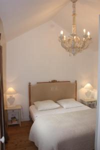 1 dormitorio con cama blanca y lámpara de araña en Maison Kador, en Crozon