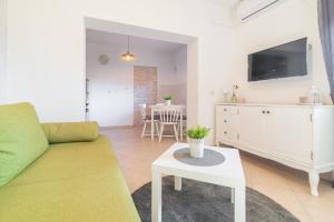 ein Wohnzimmer mit einem Sofa, einem TV und einem Tisch in der Unterkunft Mediterranean House by The Beach in Posedarje