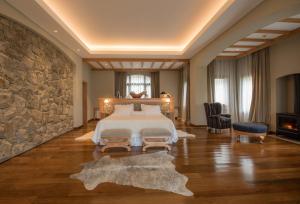 a bedroom with a bed and a stone wall at Villa Beluno Hotel & Spa in San Carlos de Bariloche