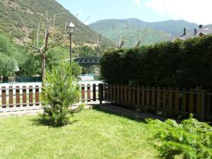 una valla de madera en un patio con montañas al fondo en Apartamentos wifi Baqueira & Aigüestortes con jardín privado, en Esterri d'Àneu