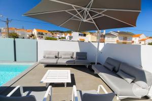 a patio with a table and chairs and an umbrella at Moderne Villa in Salir do Porto - Villa nas dunas in Salir do Porto