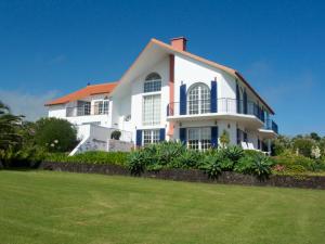 a white house with a green lawn in front of it at Lobo do Mar in Ponta Garça