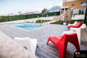 a pool with red and white chairs on a patio at Apartamentos Camino De Finisterre in Mazaricos