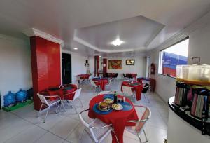 a dining room with red tables and chairs in a room at 5C Hotel in Santo Antônio de Jesus
