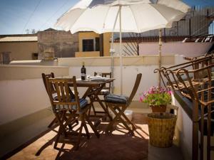 una mesa y sillas con una sombrilla en el balcón en Ortigia Guest House Casa Flora, en Siracusa