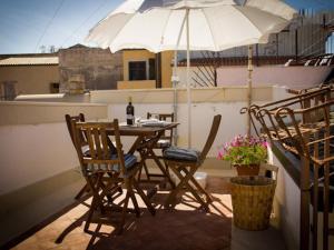 a table and chairs with an umbrella on a balcony at Ortigia Guest House Casa Flora in Syracuse