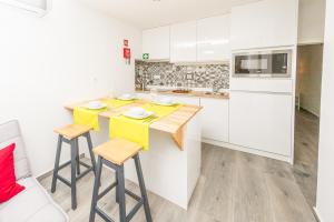 uma cozinha com armários brancos e uma ilha com dois bancos em Vieira Apartments II em Setúbal