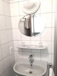 a white bathroom with a sink and a mirror at Hotel Waldschlösschen in Füchten