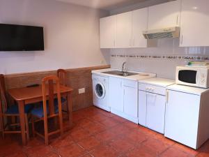 cocina con armarios blancos, mesa y microondas en Apartamentos La Tarazana 4 en La Pereda de Llanes