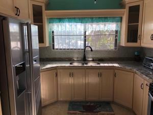 a kitchen with white cabinets and a sink and a window at A&D Tennis Villa in Arnos Vale