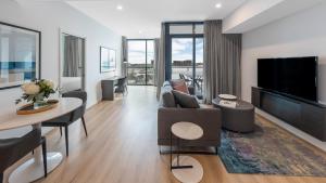 uma sala de estar com um sofá e uma televisão em Avani Adelaide Residences em Adelaide