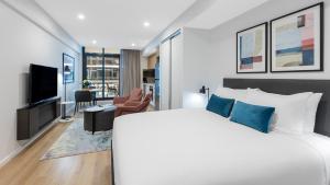 Avani Adelaide Residences في أديلايد: غرفة نوم مع سرير وغرفة معيشة