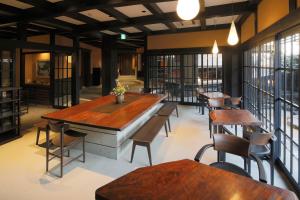 a room filled with tables and chairs and a large window at Kyomachiya Ryokan Sakura Urushitei in Kyoto