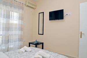 a bedroom with a bed and a tv on the wall at George apartment in Artemida