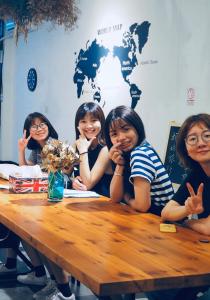 un grupo de chicas sentadas en una mesa de madera en OC Hostel, en Tainan