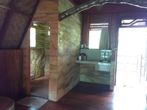 a room with a stone wall and a kitchen with a counter at On The Rocks Bungalows, Restaurant and Jungle Trekking Tours - From May to September only stay here if you are booking jungle treks with us - feel free to contact us about our Jungle Trekking services in Bukit Lawang