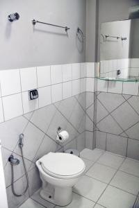 a white bathroom with a toilet and a shower at Apucarana Palace Hotel in Apucarana