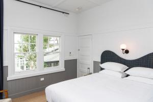 Portsea Hotel في بورتسي: غرفة نوم بسرير ابيض ونوافذ