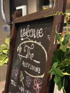 een krijtbord waarop staat: welkom in de steeg bij Alley living rama8 in Bangkok