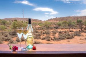a bottle of wine and two glasses on a table at Broken Hill Outback Resort in Broken Hill