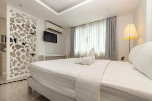 a white bedroom with a large bed and a window at Baanpoon Apartment in Chaweng