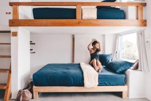 a woman sitting on a bunk bed in a bedroom at Kos One Hostel in Canggu