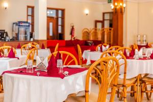 uma sala de jantar com mesas brancas e cadeiras com guardanapos vermelhos em New Safari Hotel em Arusha