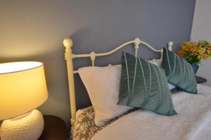 a bed with green and white pillows and a lamp at Sobe House in Yomitanson in Yomitan