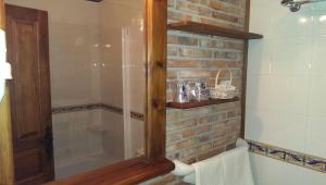 a glass shower in a bathroom with a brick wall at Hotel Rural "Posada EL SOLAR" Gintonic Bar con "Terraza panorámica puesta del sol-eclipse" in Galizano +130 photos