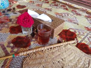 Shāhiq的住宿－Desert Private Camps - Private Bedouin Tent，一张桌子,上面放着一杯茶和红玫瑰
