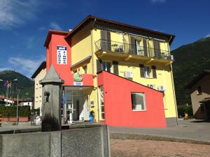 Edificio amarillo y rojo con balcón en Hotel Ristorante Camoghe, en Isone