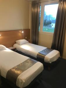 a hotel room with two beds and a window at Hotel Le Saint Aubin in Gournay-en-Bray