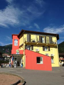 un edificio amarillo y rojo al lado de una calle en Hotel Ristorante Camoghe, en Isone