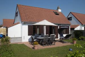 a patio with a table and chairs and an umbrella at Vakantiehuisje De Haan in De Haan