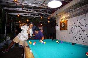 two people playing a game of pool on a pool table at Kokos Hostel Padang City in Padang