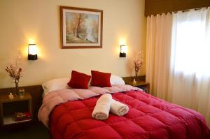 a bedroom with a large red bed with towels on it at Hostería Güemes in San Carlos de Bariloche