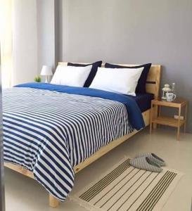 ein Schlafzimmer mit einem Bett mit einer blau-weißen gestreiften Decke in der Unterkunft Grandblue 411 in Mae Pim