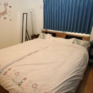 a bed with a white comforter and blue curtains at Alaha Blue Resort 6F -SEVEN Hotels and Resorts- in Chatan