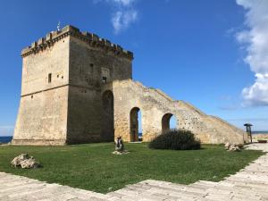 a large brick building with two towers on a grass field at DoppioBi in Torre Lapillo