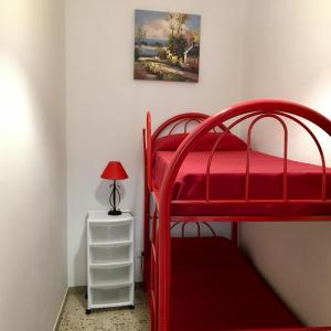a bedroom with a red bunk bed and a lamp on a night stand at Residence Arcobaleno in San Vito lo Capo