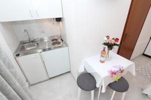 a small white kitchen with a table with flowers on it at Apartments Divna in Rovinj