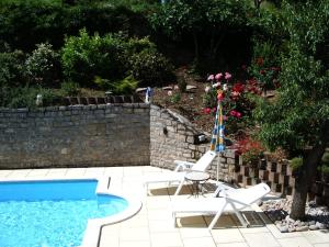 米洛的住宿－Millau Aveyron Location Vacances，游泳池旁的两把椅子和一把遮阳伞
