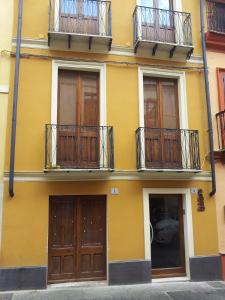 a yellow building with wooden doors and balconies at Il Palazz8 in Iglesias