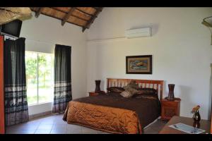 Un dormitorio con una cama grande y una ventana en Mothopo Game Lodge, en Modimolle