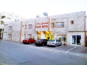 een gebouw met twee auto's geparkeerd op een parkeerplaats bij Plaza Hotel in Muscat