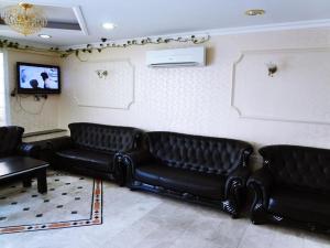 una sala de espera con sofás de cuero negro y TV en Plaza Hotel, en Mascate