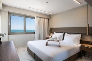 a hotel room with a large bed and a window at Porto Platanias Beach Luxury Selection - Adults Only in Plataniás