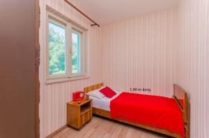 a bedroom with a red bed and a window at House Marina in Zaboric